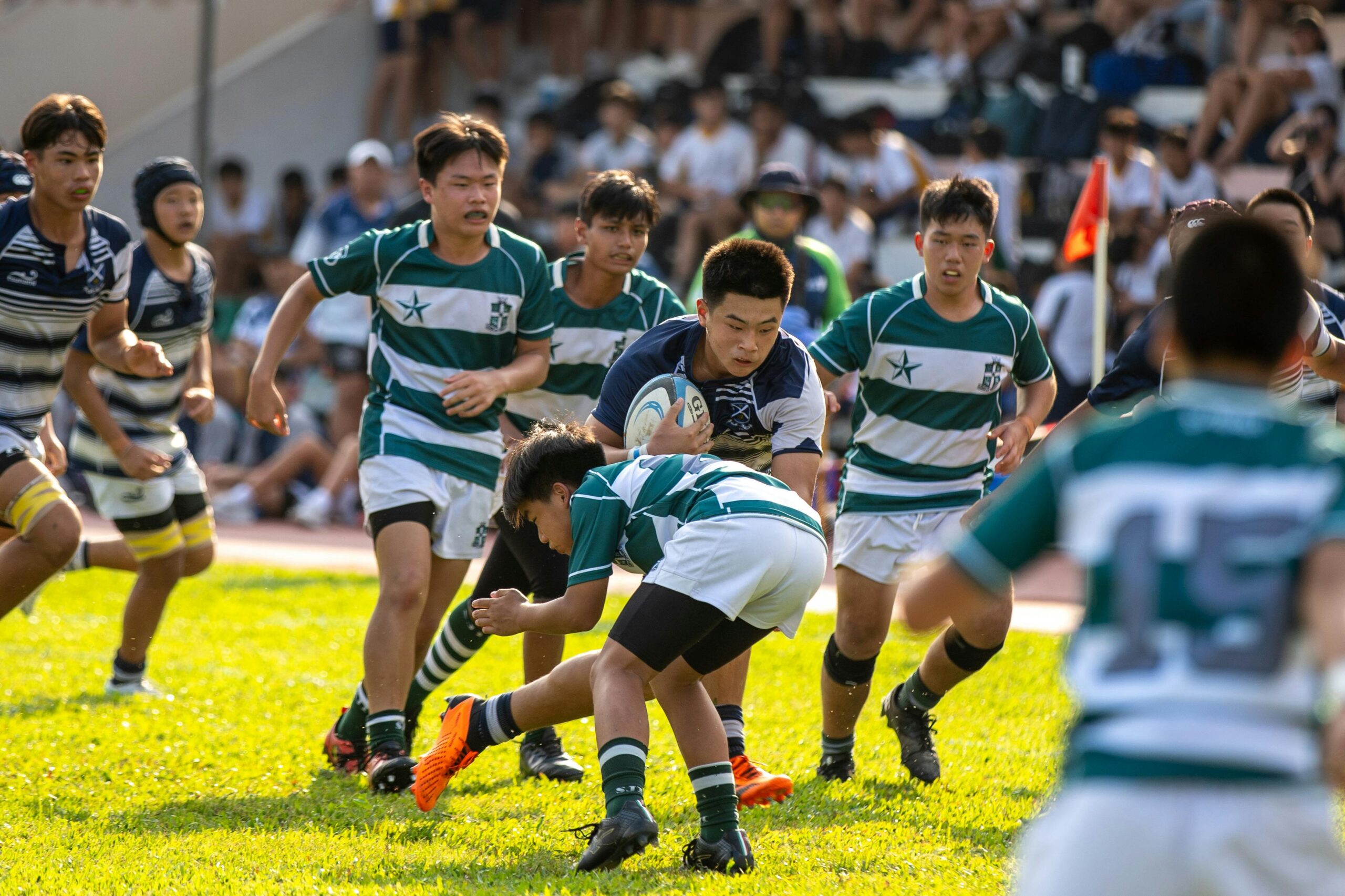 Intense high school rugby match with players in action during a sunny day.